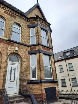 a large brick building with a white door and windows at Anfield Haven in Liverpool