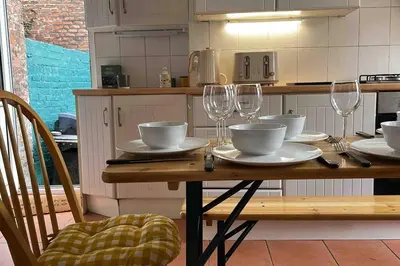 a wooden table with bowls and wine glasses on it at Anfield Haven in Liverpool