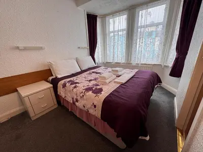 a bedroom with a bed with purple sheets and a window at OYO Delton Hotel Blackpool Pleasure Beach in Blackpool