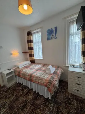 a bedroom with a bed and two windows at OYO Delton Hotel Blackpool Pleasure Beach in Blackpool
