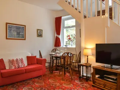 a living room with a red couch and a table at Kiln Cottage in Bolton le Sands