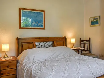 a bedroom with a bed with two lamps and two chairs at Kiln Cottage in Bolton le Sands