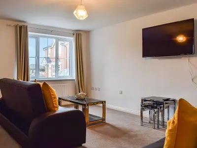 a living room with a couch and a tv on the wall at The Goldsmith in Blackpool