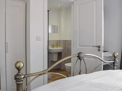 a bedroom with a bed and a bathroom with a sink at The Goldsmith in Blackpool