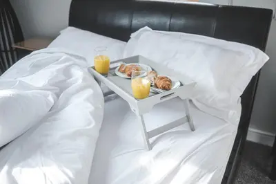 a tray of food on a bed with two glasses of orange juice at The Coach House Heysham in Heysham