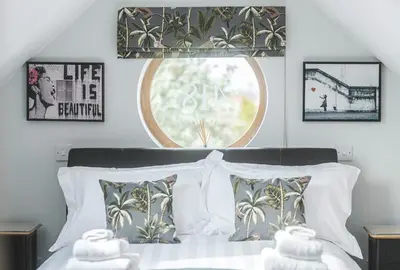 a bedroom with a bed with pillows and a window at The Coach House Heysham in Heysham
