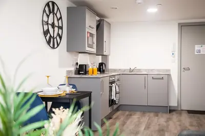 a kitchen with grey cabinets and a table at Modern 1-Bedroom Liverpool Apartment, Cosy & Fast Wi-Fi in Liverpool