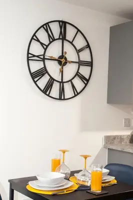 a clock on a wall above a table with plates and glasses at Modern 1-Bedroom Liverpool Apartment, Cosy & Fast Wi-Fi in Liverpool