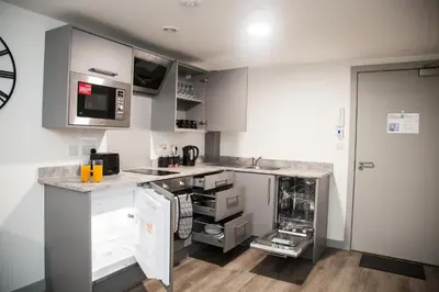 a kitchen with gray cabinets and white appliances at Modern 1-Bedroom Liverpool Apartment, Cosy & Fast Wi-Fi in Liverpool