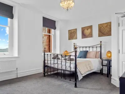 a bedroom with a bed and a chandelier at Mulberry Beautiful Apartment with Sea View - Pass the Keys in Grange Over Sands