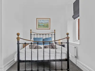 a black bed in a room with white walls at Mulberry Beautiful Apartment with Sea View - Pass the Keys in Grange Over Sands