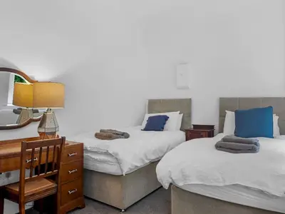 a bedroom with two beds and a desk with a mirror at Mulberry Beautiful Apartment with Sea View - Pass the Keys in Grange Over Sands