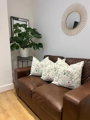 a brown leather couch in a living room with a mirror at 2025 Award Winner Liverpool Cherry House - 4 Bedrooms in Liverpool