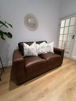 a brown leather couch in a living room with a mirror at 2025 Award Winner Liverpool Cherry House - 4 Bedrooms in Liverpool