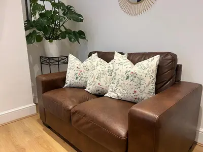 a brown leather couch with four pillows on it at 2025 Award Winner Liverpool Cherry House - 4 Bedrooms in Liverpool