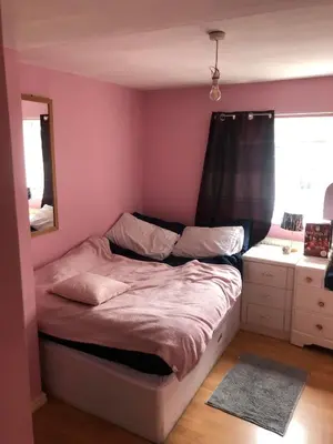 a bedroom with a bed with a pink wall at Room in town centre in Saint Helens
