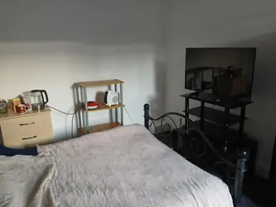 a bedroom with a bed and a dresser and a table at Room in town centre in Saint Helens