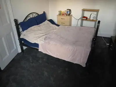 a bedroom with a large bed with blue sheets at Room in town centre in Saint Helens