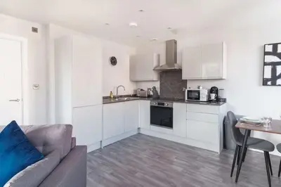 a kitchen with white cabinets and a couch and a table at Modern 1 Bedroom Liverpool Apartment in Liverpool