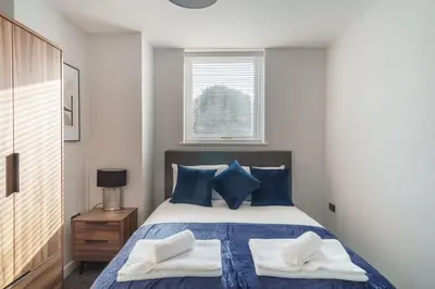 a bedroom with a bed with blue pillows and a window at Modern 1 Bedroom Liverpool Apartment in Liverpool