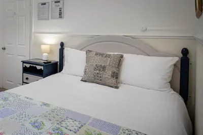 a bedroom with a white bed with a quilt on it at The Wescoe Guesthouse in Blackpool