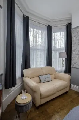 a living room with a couch in front of windows at The Wescoe Guesthouse in Blackpool