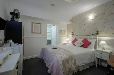 a bedroom with a large bed with pink pillows at The Wescoe Guesthouse in Blackpool
