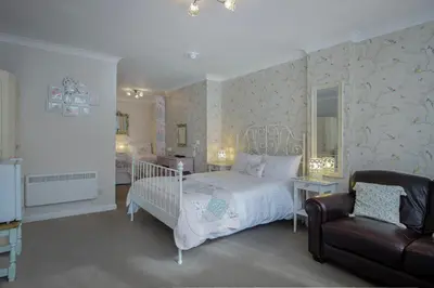 a bedroom with a white bed and a chair at The Wescoe Guesthouse in Blackpool