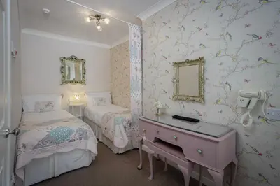a bedroom with two beds and a desk with a mirror at The Wescoe Guesthouse in Blackpool