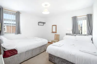 two beds in a room with white walls and windows at SuiteSpot Serviced Apartments Blackpool in Blackpool