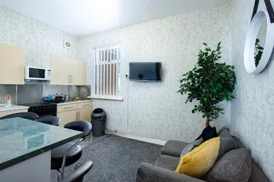 a kitchen and a living room with a plant in the corner at SuiteSpot Serviced Apartments Blackpool in Blackpool