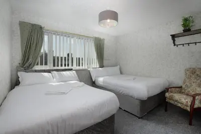 a hotel room with two beds and a chair at SuiteSpot Serviced Apartments Blackpool in Blackpool