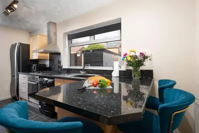 a kitchen with a black counter top and blue chairs at Alexandra - WiFi Parking Garden in Walton le Dale