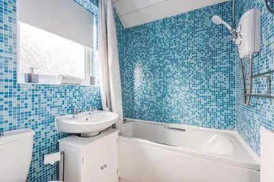 a blue tiled bathroom with a sink and a tub and a toilet at Alexandra - WiFi Parking Garden in Walton le Dale