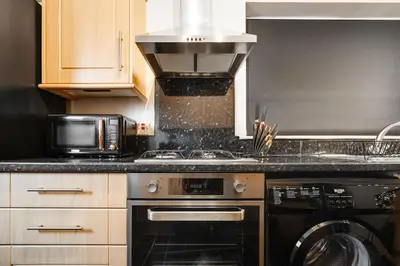 a kitchen with a stove and a microwave at Alexandra - WiFi Parking Garden in Walton le Dale