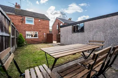a picnic table and two benches in a yard at Alexandra - WiFi Parking Garden in Walton le Dale