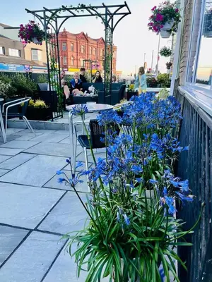 a patio with blue flowers and a table and chairs at The Danescourt in Blackpool