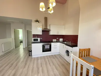 a kitchen with white cabinets and a washer and dryer at Liverpool City Stays - Bold Street in Liverpool