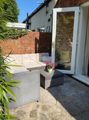 a patio with a couch and a table with flowers at Leafy lodge in Lytham in Brown Moss Side
