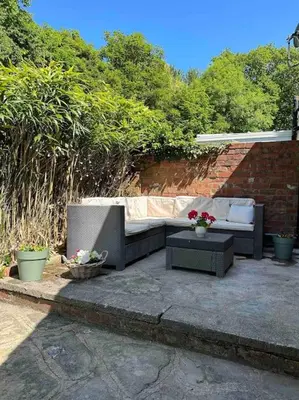 a patio with a couch and a table with flowers at Leafy lodge in Lytham in Brown Moss Side