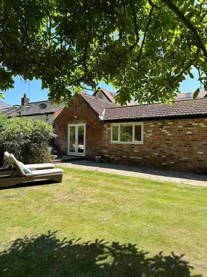 a brick house with a bench in a yard at Leafy lodge in Lytham in Brown Moss Side