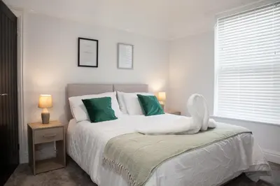a white bedroom with a bed with green pillows at 8 Karslake Road in Wallasey