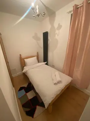 a small bedroom with a bed and a chandelier at 2 Bedroom New Flat In Blackpool Town Center in Blackpool