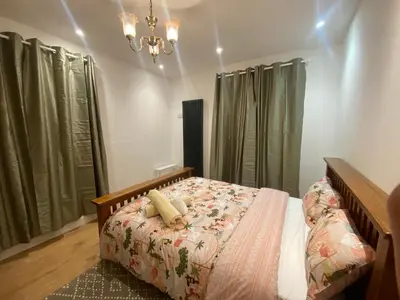 a bed in a bedroom with green curtains and a chandelier at 2 Bedroom New Flat In Blackpool Town Center in Blackpool