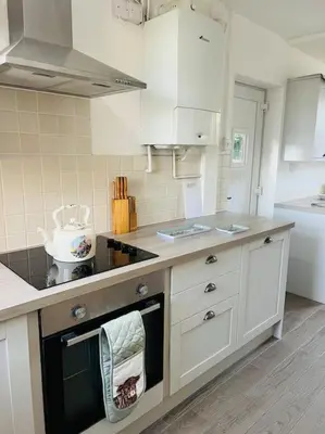 a kitchen with white cabinets and a stove top oven at Willow Cottage - Billinge Wigan, sleeps 4 , parking and garden in Billinge