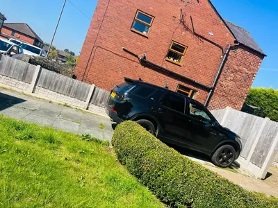 a black car parked in front of a brick building at Willow Cottage - Billinge Wigan, sleeps 4 , parking and garden in Billinge