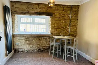 a table and chairs in a room with a stone wall at Willow Cottage - Billinge Wigan, sleeps 4 , parking and garden in Billinge