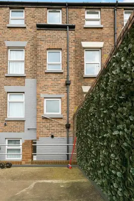 a brick building with a green hedge in front of it at Sidemersey Livings - Botanical Hidden Gems, Magical Gardens in Liverpool