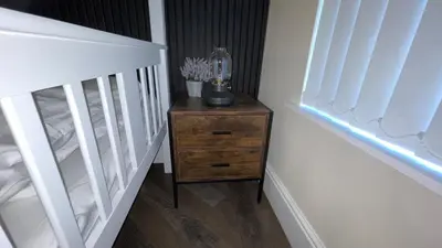 a small wooden dresser in a bedroom with a crib at ANFIELD PLACE TO STAY in Liverpool