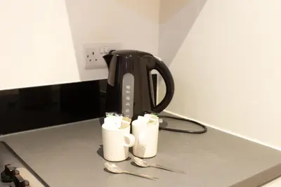 a coffee pot and two cups on a kitchen counter at Cosy Studio Apt in Preston near City Centre in Preston